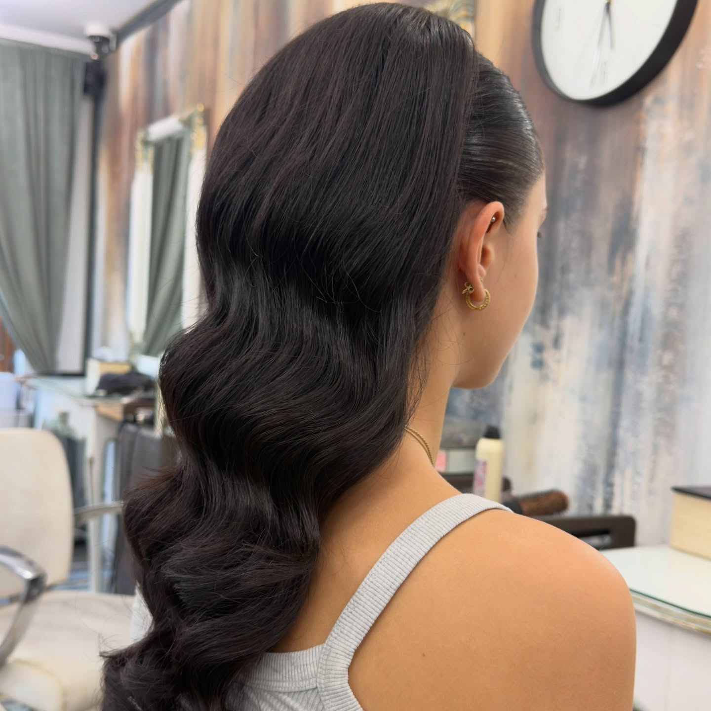 Coafură cu bucle hollywood pe păr închis la culoare, în salon